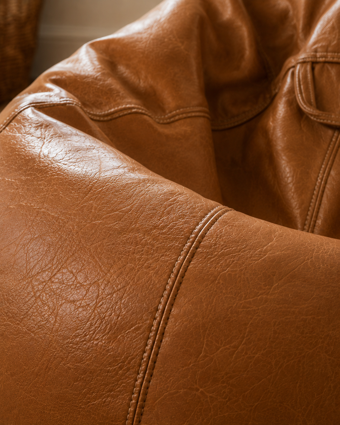 Détail des coutures et de la texture du pouf en simili cuir cognac Mowana avec finition premium effet cuir vieilli