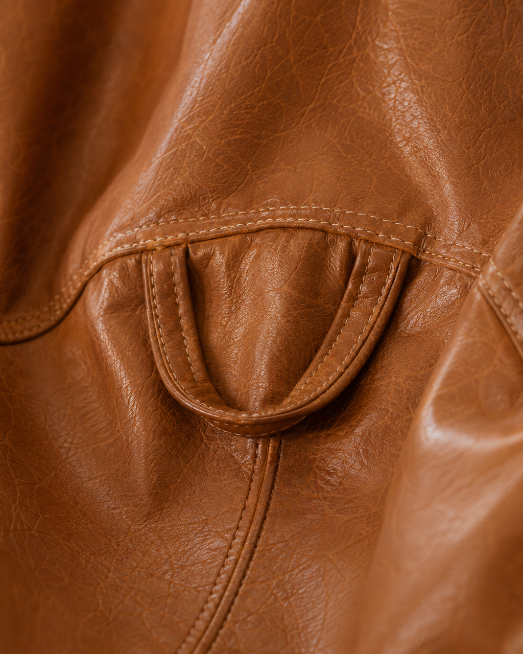 Détail de la poignée intégrée du pouf en simili cuir cognac Mowana avec finition premium et coutures visibles