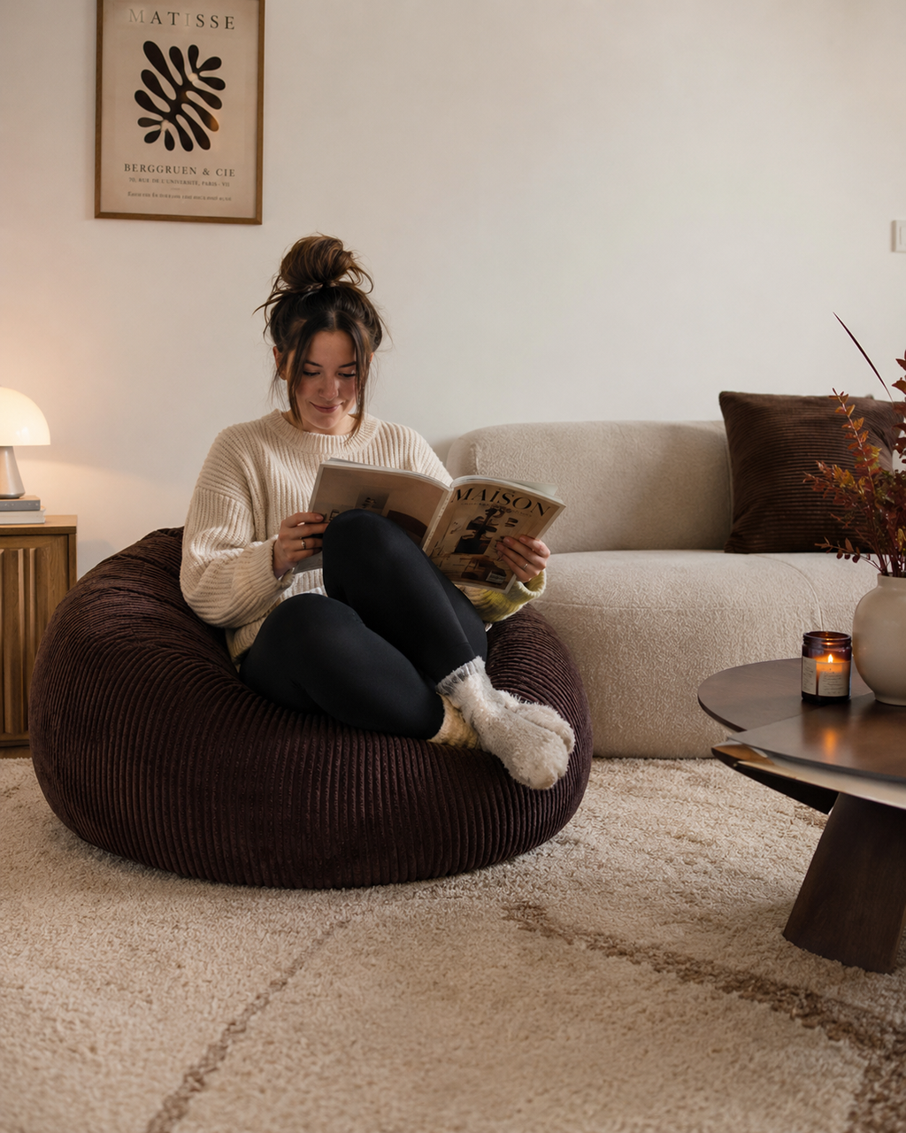 Femme assise dans un pouf côtelé moka Mowana en train de lire dans un salon beige chaleureux à l’ambiance cocooning