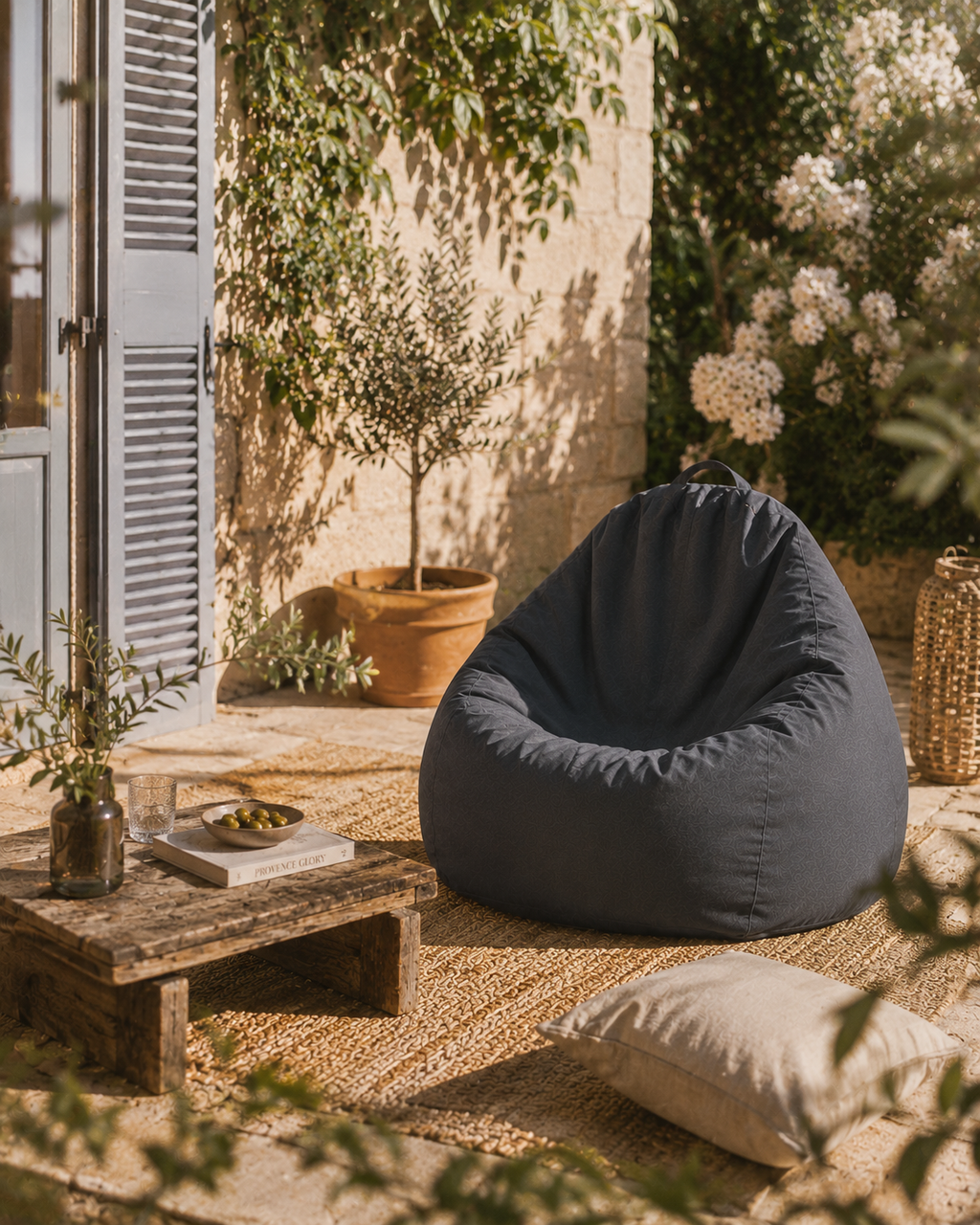 Pouf extérieur gris anthracite Mowana installé sur une terrasse méditerranéenne avec ambiance jardin ensoleillé et décoration naturelle