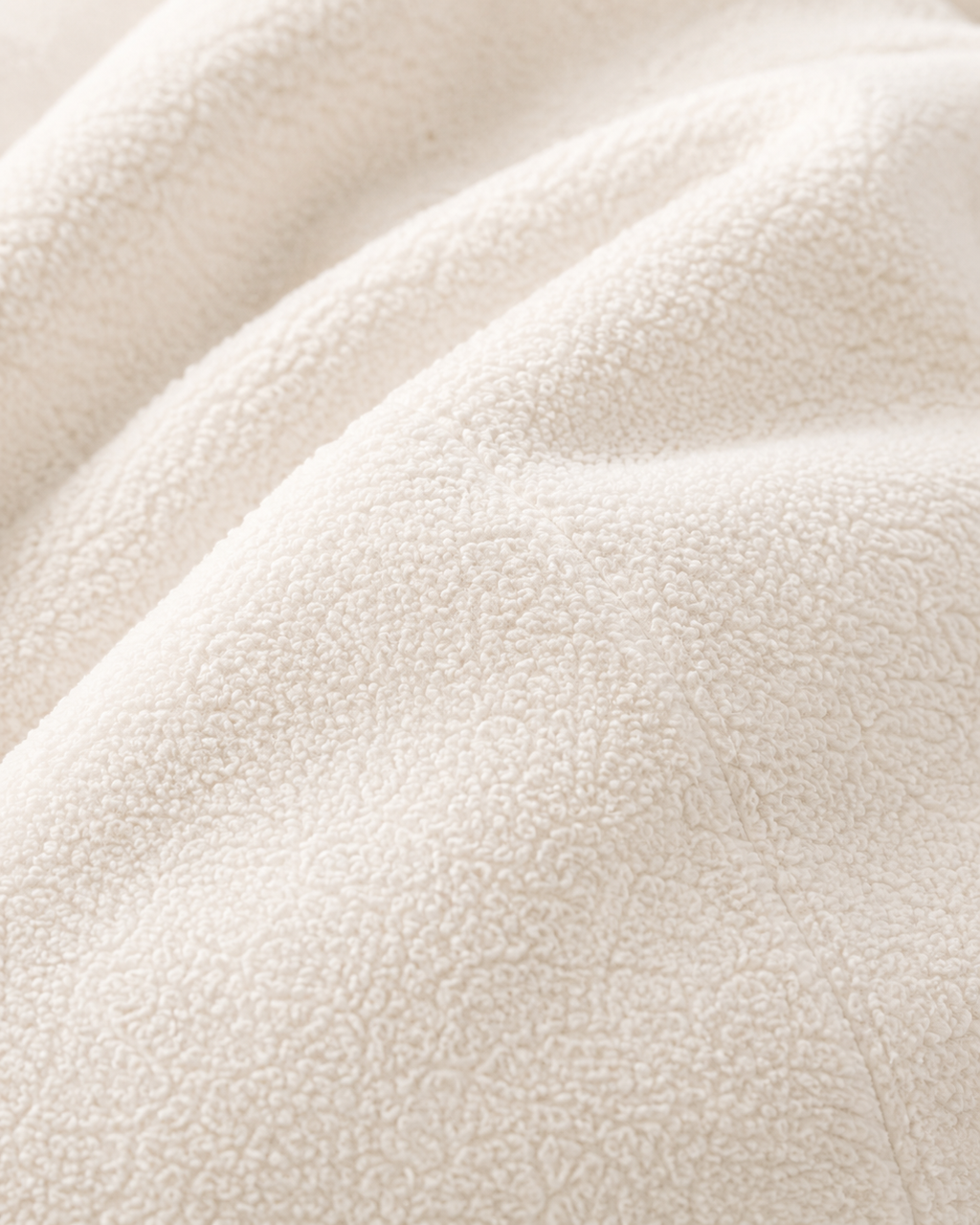 Gros plan sur la texture bouclée douce du pouf velours blanc Mowana
